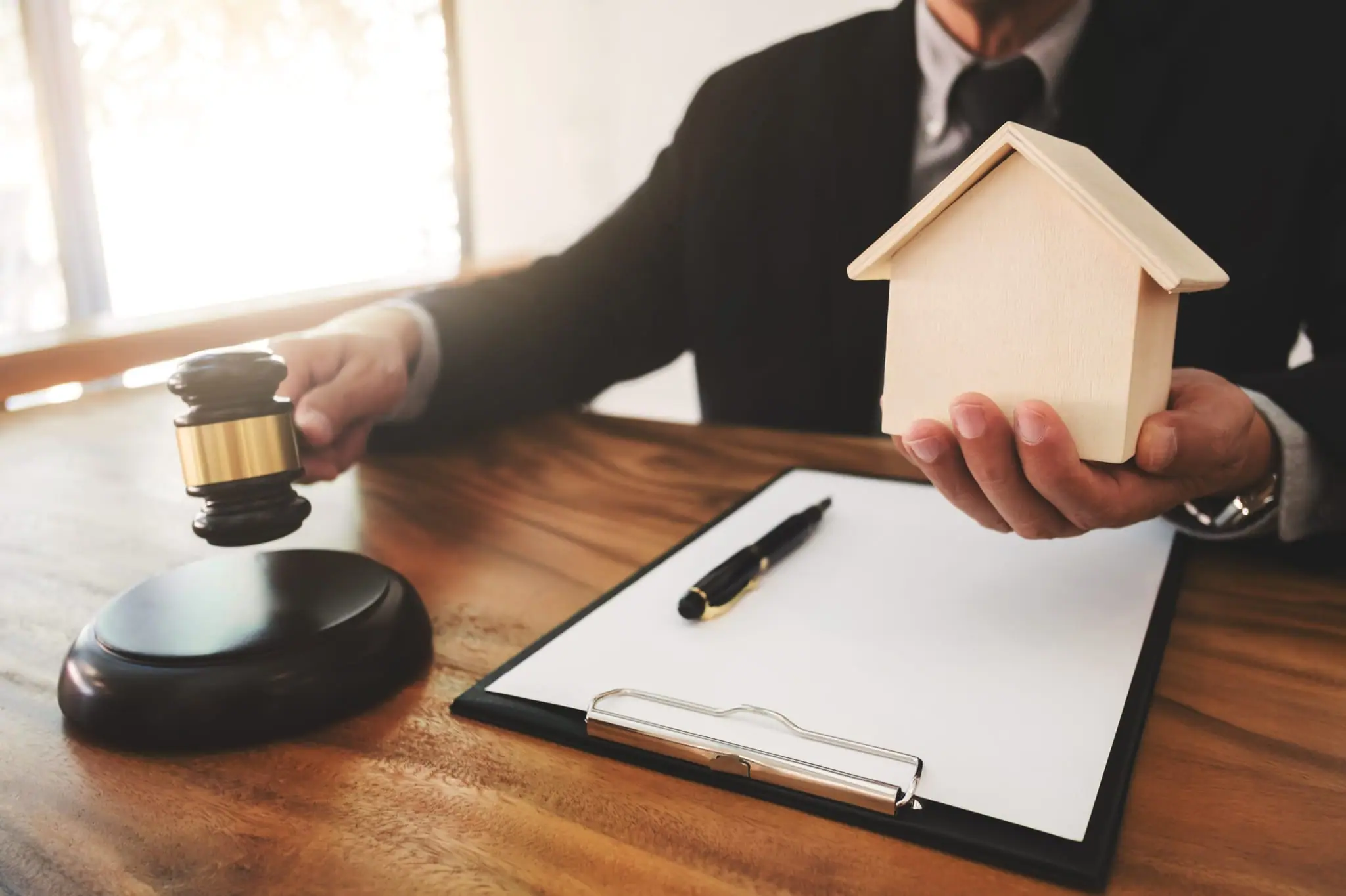 An auction gavel beside a model house