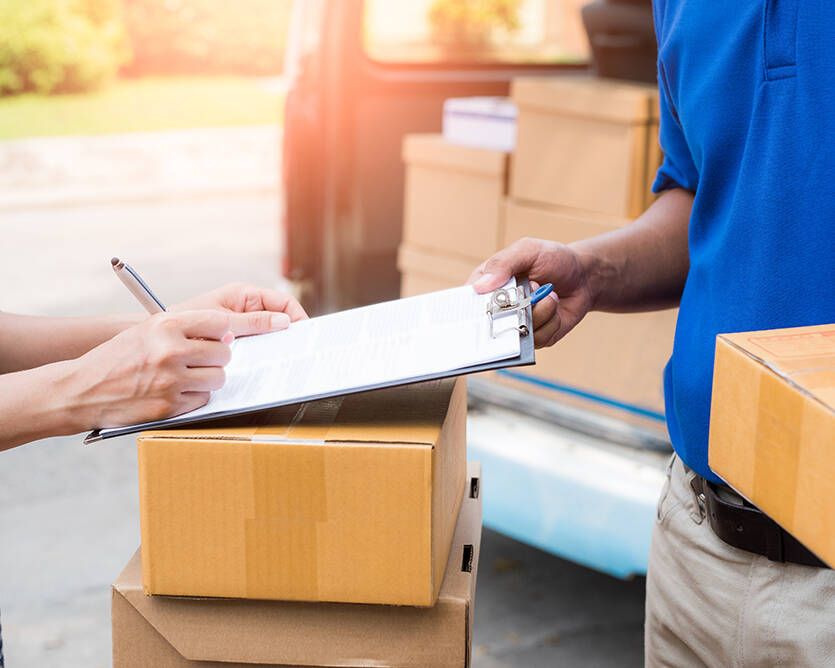 Person signing paperwork on clipboard surrounded by moving boxes