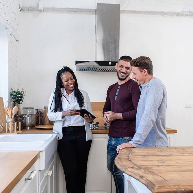 Realtor showing tablet to couple in kitchen