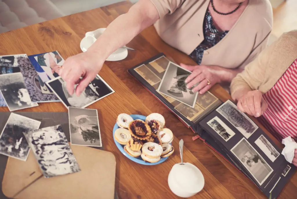 Two women looking through old family photos at a table