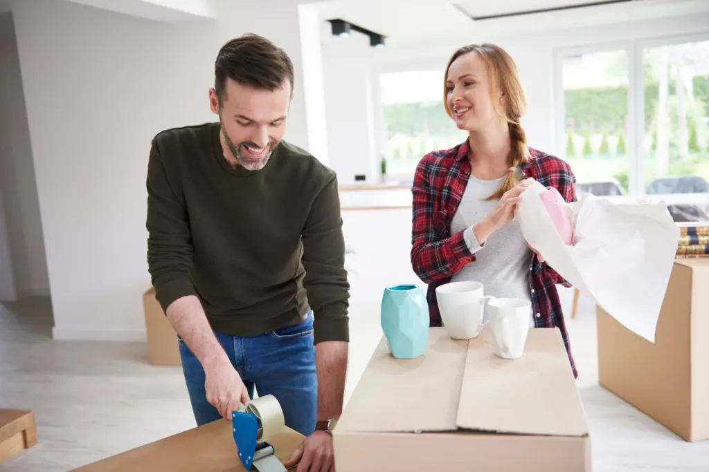 A couple packing and taping moving boxes
