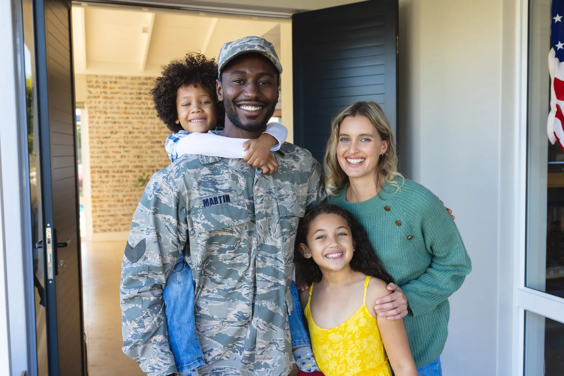 A service member and his family at their front door